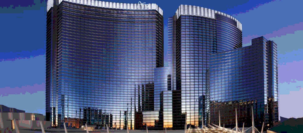 An image of the Aria hotel in Las Vegas showing the illuminated marquee and curving profiles of the buildings.