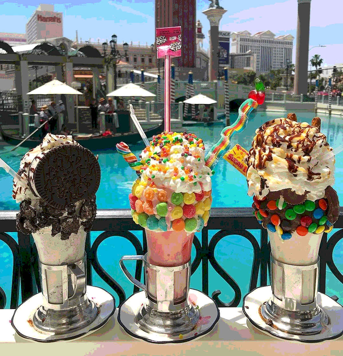 An array of three ornately decorated milkshakes with candy and other edibles