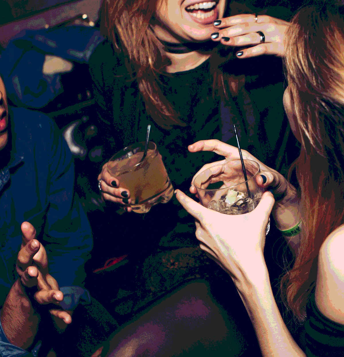 Two ladies and a gentleman share laughs over drinks in a nightclub
