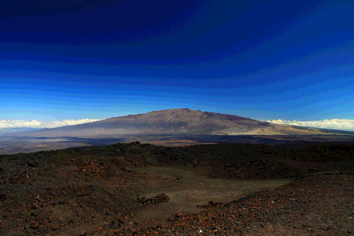 A view toward Mauna Kea volcano in the distance, with a desolate foreground of volcanic terrain