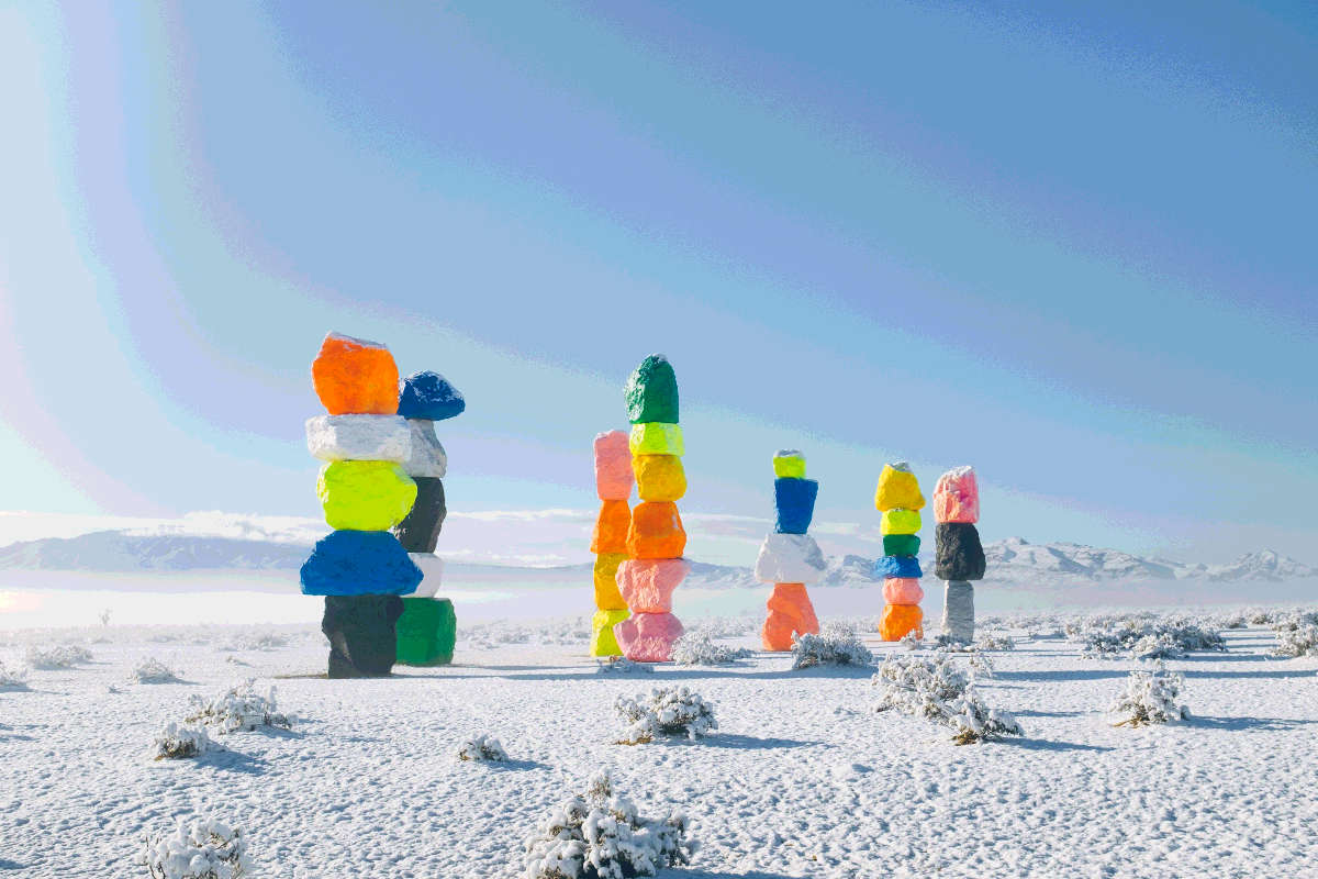Seven stacks of vibrantly colored rocks with surroundings covered in light snow